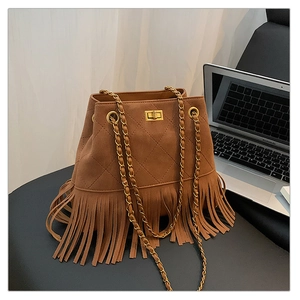 Close-up of brown suede bucket bag featuring fringe details and quilted stitching