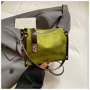 Detail of green suede crossbody bag featuring white diamond stitching and silver rivets