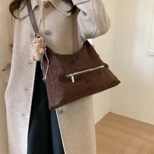 Détail du sac hobo en daim marron foncé avec fermeture éclair et breloque ours en peluche