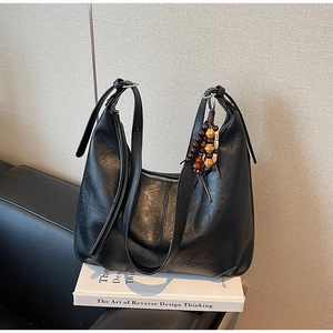 Detail of black vintage hobo bag texture featuring decorative wooden bead charm