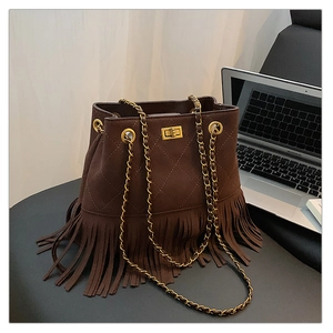 Macro detail of dark brown suede bucket bag featuring diamond quilting and tassel fringe