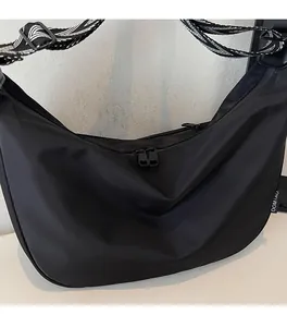 Detail view of black nylon crescent bag featuring double zippers and geometric woven strap