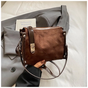Detail of brown suede crossbody bag with quilted stitching and faux patent leather trim