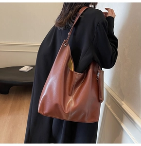 Grande borsa tote terracotta con cuciture a contrasto indossata da una modella in cappotto nero