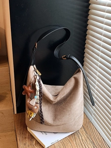 Grand sac cabas hobo taupe avec charms décoratifs posé sur une table en bois