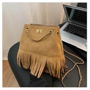 Close-up of brown suede bucket bag featuring diamond quilting and long tassel fringe details