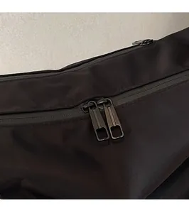 Close-up of waterproof dual zippers and brushed metal hardware on oxford fabric bag