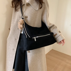 Détail du sac hobo en daim noir avec fermeture éclair argentée et breloque ours