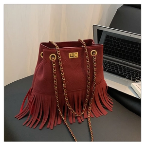 Detailed close-up of a burgundy bucket bag with quilted patterns and long tassels on a chair
