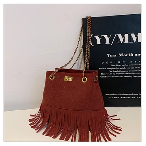 Detail of red-brown suede bucket bag featuring quilted patterns and long fringe tassels