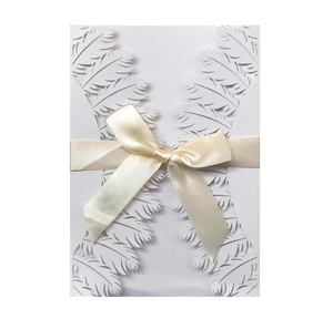Detailed laser-cut white wedding invitation featuring feather texture and a cream satin bow