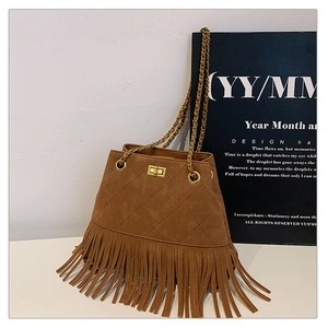Detail of brown suede bucket bag featuring quilted pattern, fringe, and gold chain strap