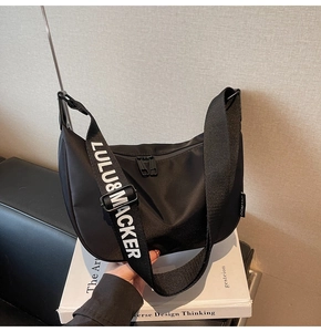 Detail of black nylon dumpling bag featuring branded letter printed wide shoulder strap
