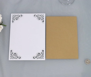 Detail of laser cut wedding invitation set with white ornate cover and kraft paper inner sheet