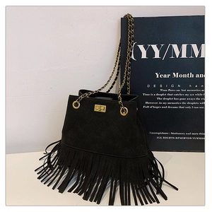 Detailed view of black quilted suede bucket bag with long fringe and gold chain strap