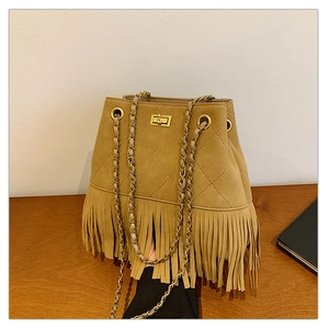 Close-up of camel suede bucket bag with diamond stitching, gold chain, and long fringes