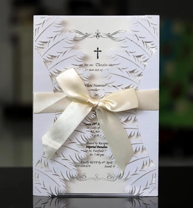 Detail of laser-cut white feather invitation with a satin bow and religious text