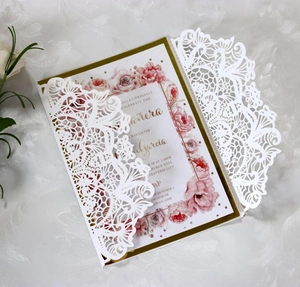 Close-up of laser cut lace invitation with elegant floral watercolor insert card