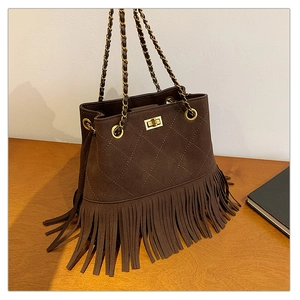 Close-up of quilted coffee suede bucket bag with long fringe and golden chain strap