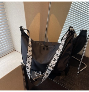 Close-up of minimalist black nylon crescent bag with stylish geometric patterned strap