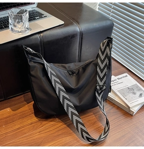 Detail of black nylon crescent bag with adjustable herringbone strap and metal zipper