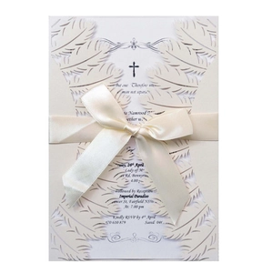 Elegant laser cut cream wedding invitation with feather pattern and satin ribbon bow