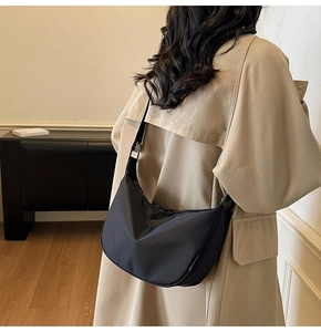 Minimalist black oxford crossbody crescent bag shown on shoulder from a side-rear view