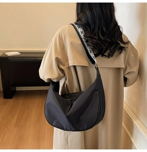 Detail of black nylon crescent bag featuring a stylish black and white geometric woven strap