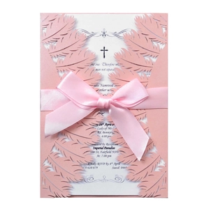 Detail of pink laser-cut wedding invitation with satin ribbon bow and feather texture