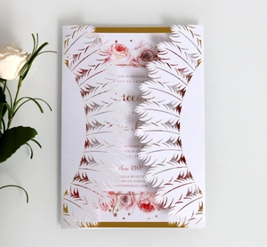 Elegant white laser-cut wedding invitation with feather design and pink floral inner card