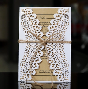 Détail de l'invitation de mariage blanche découpée au laser avec papier kraft et ficelle