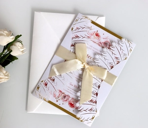 Laser cut wedding invitation set with white feathers and gold satin ribbon bow