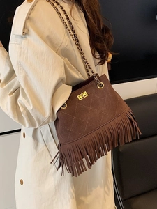 Vintage brown suede bucket bag with long tassels and gold chain strap shown on model