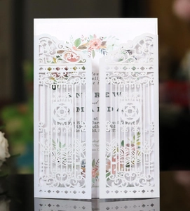 Detail of laser-cut white wedding invitation with elegant baroque floral patterns