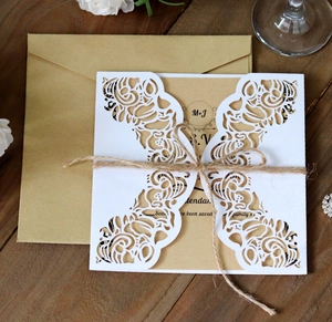 Gros plan d'une invitation en dentelle découpée au laser avec papier kraft et ficelle
