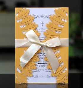 Detail of laser-cut feather pattern on invitation with silk bow and elegant typography
