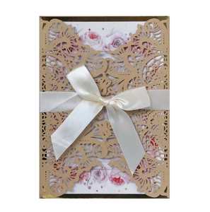 Detail of laser-cut invitation card with golden filigree and elegant satin ribbon bow