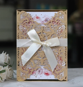 Detail of laser-cut invitation featuring a silk bow and floral interior card