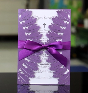 Macro detail of laser-cut purple feather pattern invitation with a silk ribbon bow