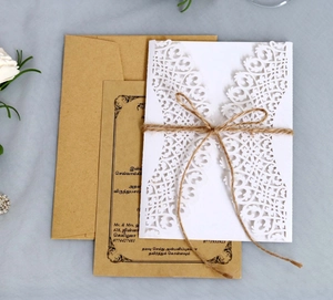 Détail de l'invitation florale découpée au laser avec enveloppe kraft et nœud en ficelle