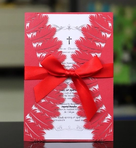 Detail of laser-cut red feather invitation with elegant satin bow and printed insert