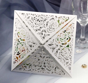 Detail of white laser-cut rose floral wedding invitation cover with elegant inner card
