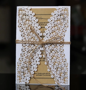 Close-up of laser cut hollow invitation cover with kraft paper insert and hemp rope bow