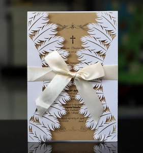 Detail of laser-cut white feather wedding invitation with a satin bow and kraft insert