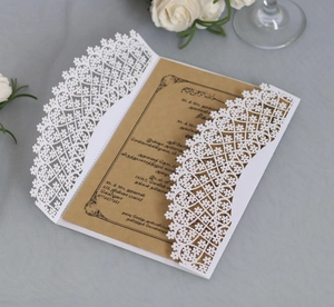Detailed laser cut floral design on white wedding card sleeve with kraft paper insert