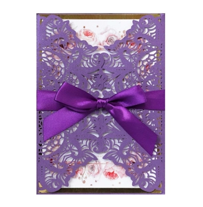 Detail of laser-cut dark purple invitation with elegant satin bow and floral inner card