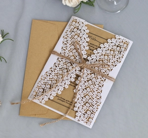 Close-up of laser-cut floral wedding invitation with kraft insert and jute twine