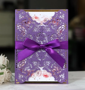 Detail of laser-cut purple invitation with satin ribbon and floral pattern