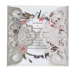 Macro shot of silver glitter laser-cut wedding invitation with floral inner card