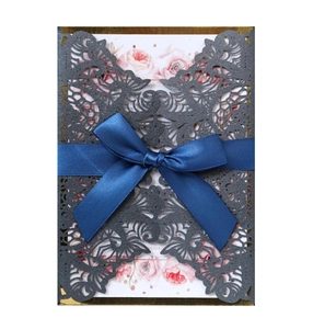 Detail showing the laser-cut lace design and blue satin ribbon on wedding invitation